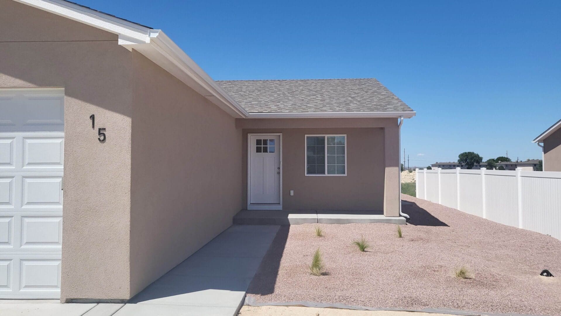 Newly constructed single story house with beige exterior and clear blue sky.