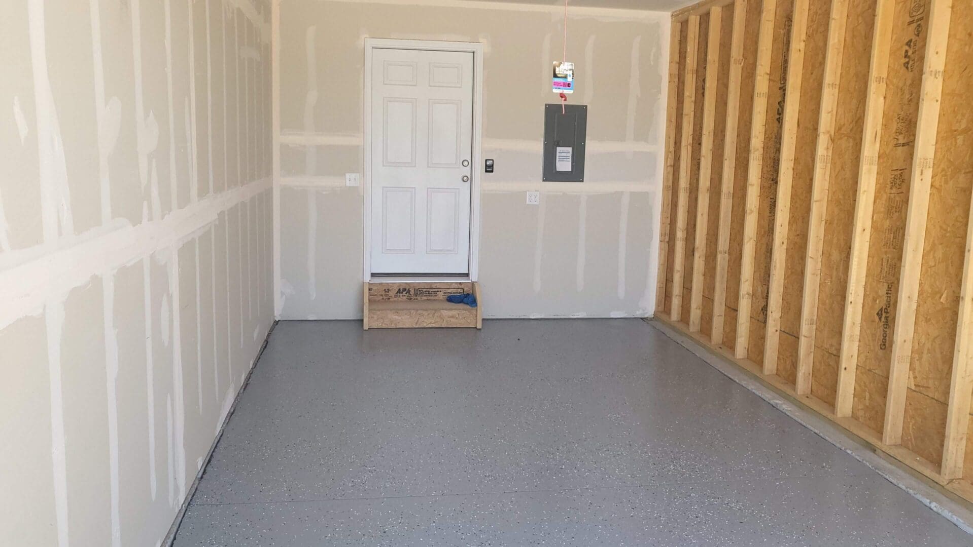 Empty garage with door and unfinished wall.