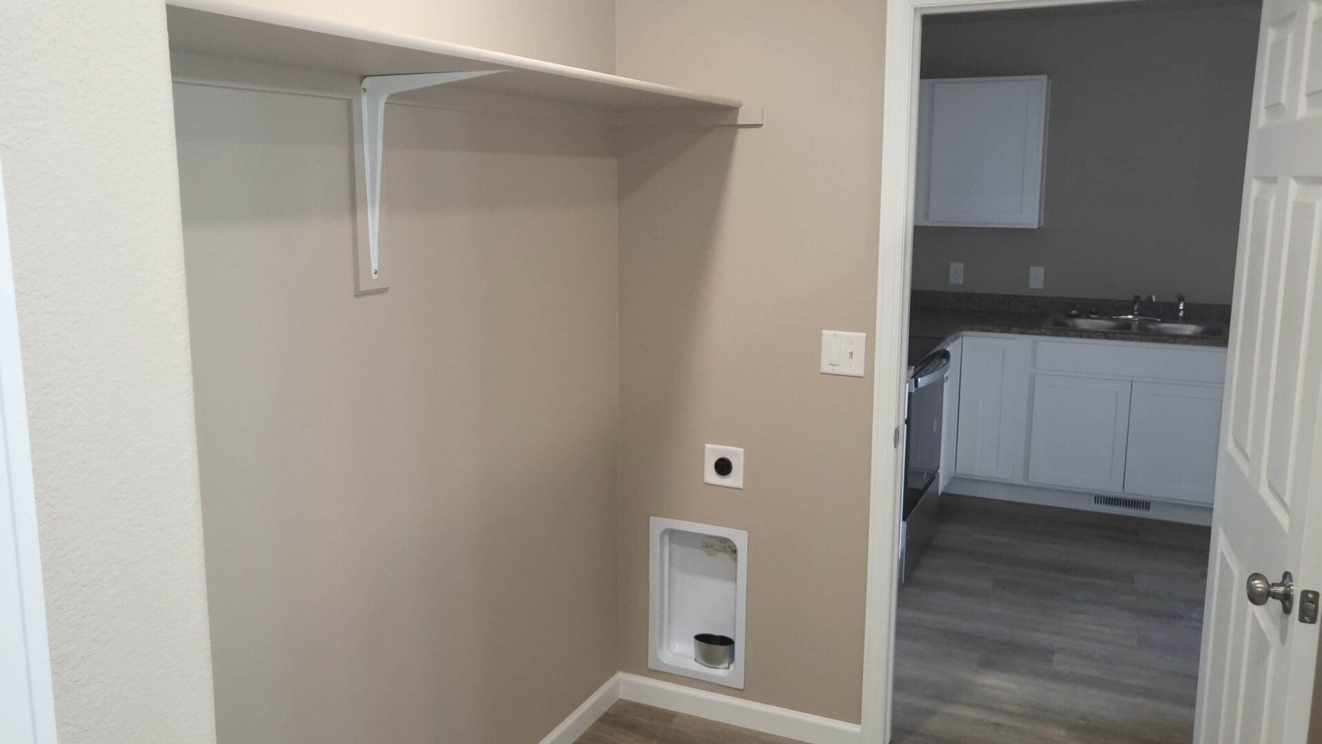 Laundry area with shelf and kitchen view.