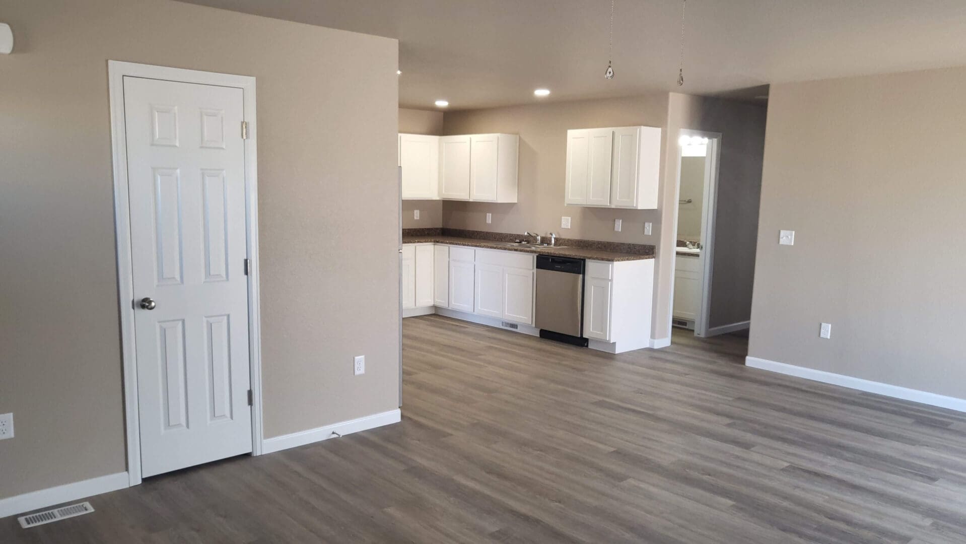 Modern kitchen and living area with wood flooring.
